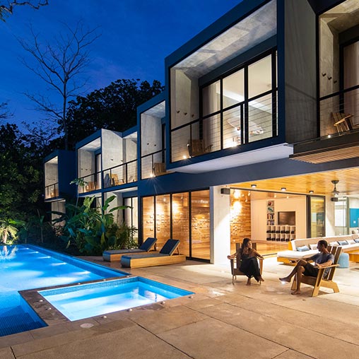 A house with a pool and a person sitting on a bench.