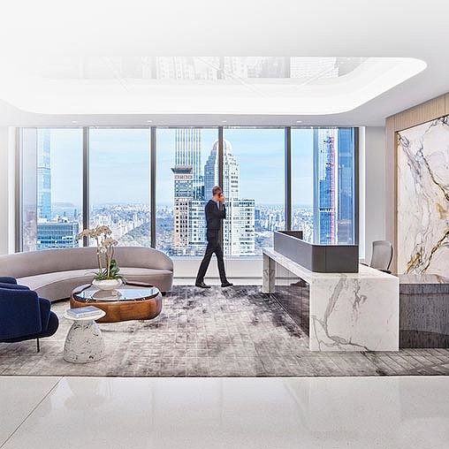A person standing in a room with a large window and a large city.