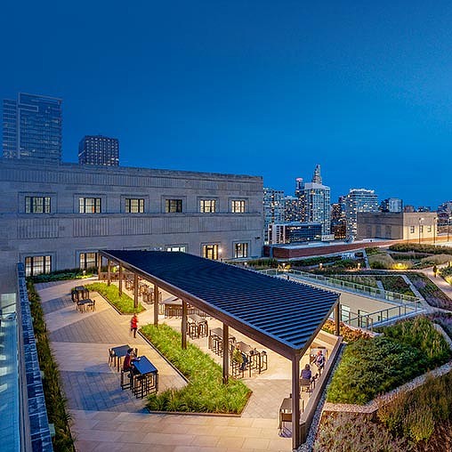 A building with a pool and a walkway with people sitting on it.
