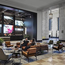 A man and woman sitting in a room with large screens.