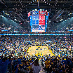 A crowd of people in a basketball stadium.