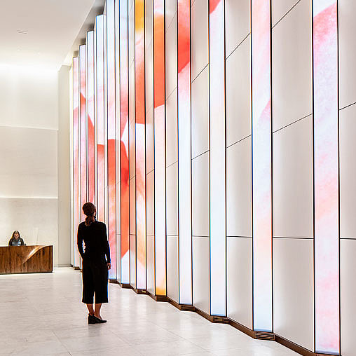 A person standing in a room with a wall of art.