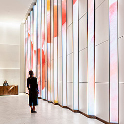A person standing in a room with a wall of art.