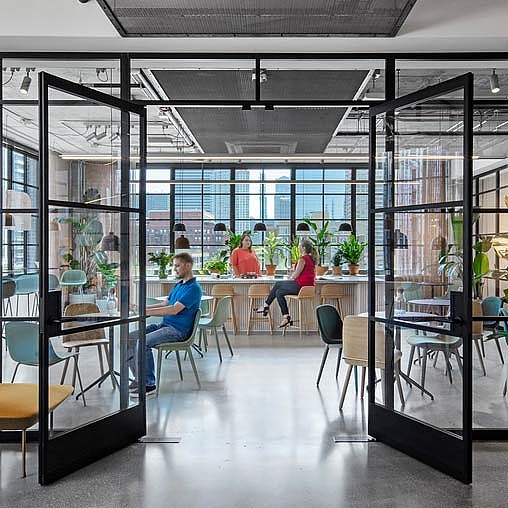 A group of people sitting at a table in a room with glass walls.