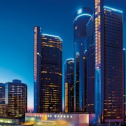 A group of tall buildings with Renaissance Center in the background.
