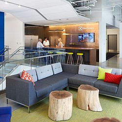 A group of people standing in a room with a bar and couches.