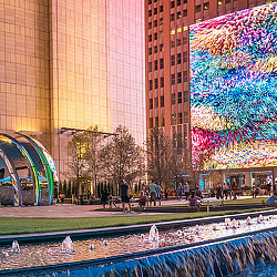 A group of buildings with trees and a fountain in front of them.