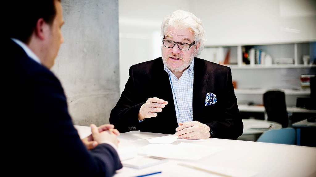 A man sitting at a table talking to another man.