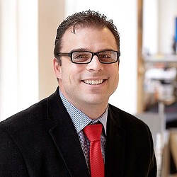 A man wearing glasses and a suit.