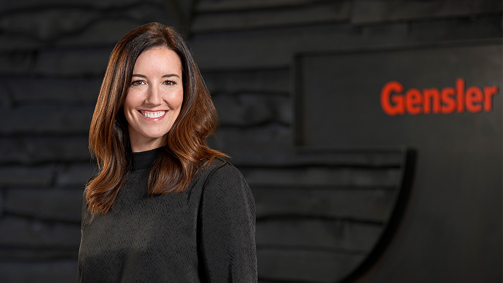 A woman smiling in front of a wall.