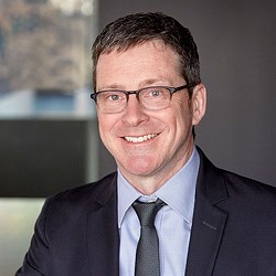 A man wearing glasses and a suit.