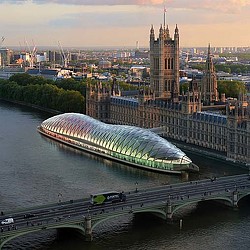 A large building with a bridge over a river with a city in the background.