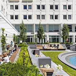 A building with a pool and people sitting at tables.