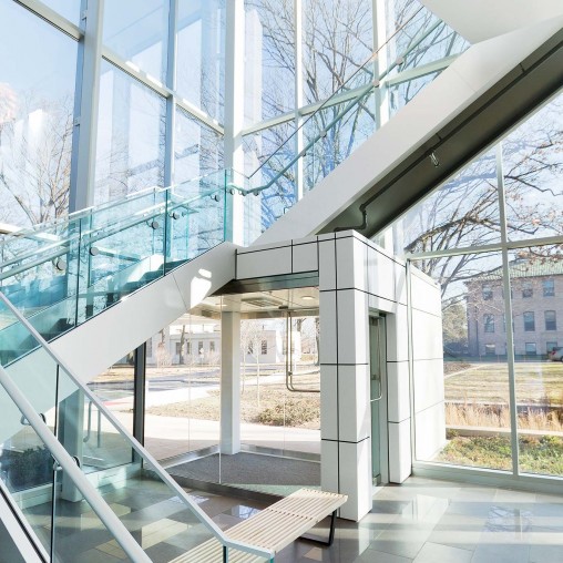 A glass walled building with a bench.