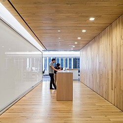 A man and woman kissing in a room with a wood floor and white walls.