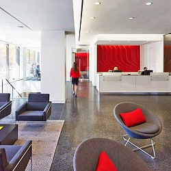 A person walking in a room with chairs and a red curtain.