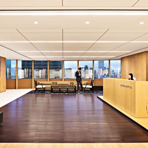 A person standing in a room with a large window and a wood floor.