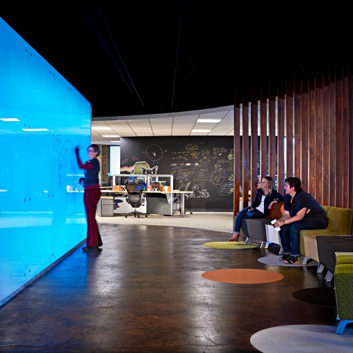 A person standing in a room with people sitting on chairs.
