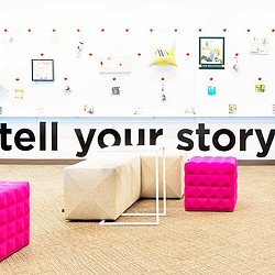 A white chair in front of a wall with pictures on it.