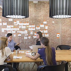 A group of people sitting at a table with papers on it.