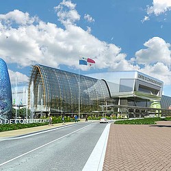 A large stadium with a road and cars in front.