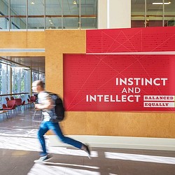 A person running in front of a large red sign.