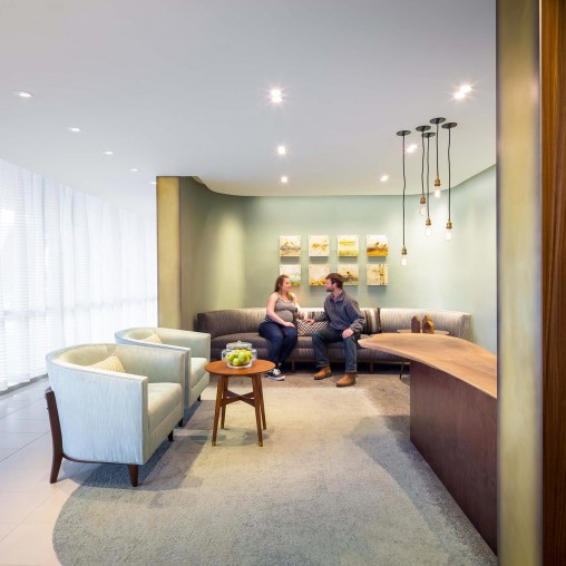 A couple of people sitting on a couch in a room with a window.