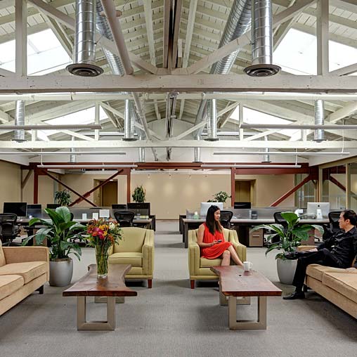 A couple of people sitting in a room with plants and a glass ceiling.