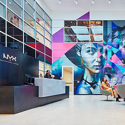 A man and woman sitting on a bench in front of a large screen.