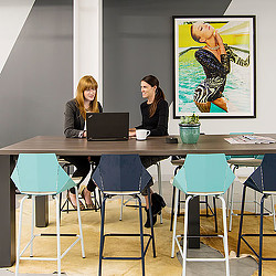A couple of women sitting at a table with a laptop.