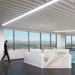 A person standing in a room with large windows and a large white table.