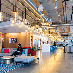 A person sitting on a bench in a large room with people.