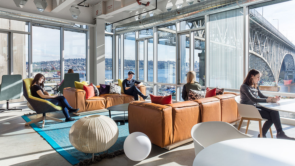 A group of people sitting in a room with a large window.