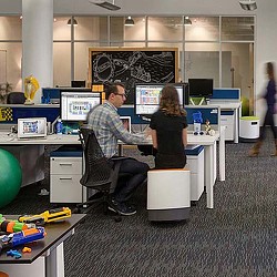 A man and a woman sitting at a desk with computers.