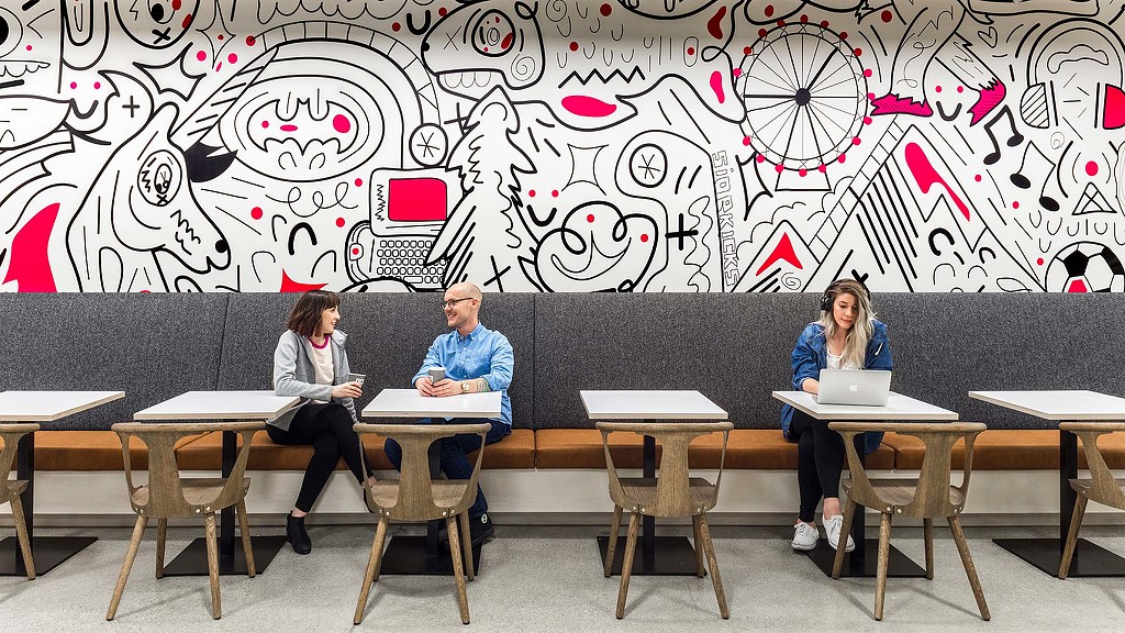 A group of people sitting at a table with laptops.