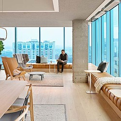 A person sitting in a room with a large window and a large city.