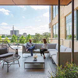 A man and woman sitting on a couch in a room with a large window and a table with.