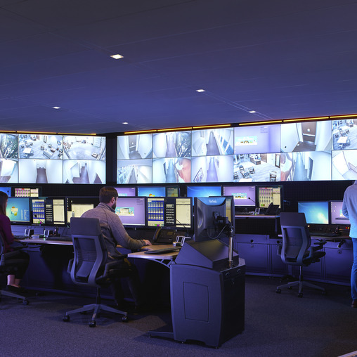 A person sitting at a desk with multiple computers.