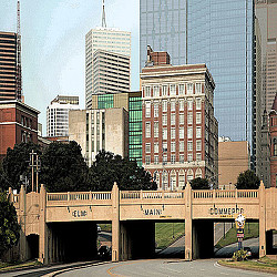 A bridge with a road and buildings in the background.