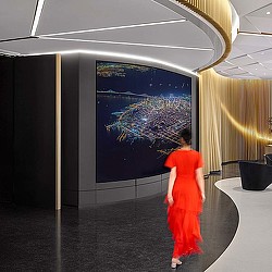 A person in an orange dress looking at a large screen.