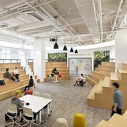 A group of people sitting in a room with tables and chairs.