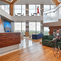 A person sitting on a couch in a room with a large window.