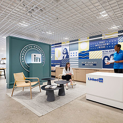 A person sitting on a bench in a room with a large screen.