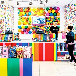 A child in a room with a wall of balloons and a girl.