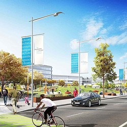 A person riding a bicycle on a street with a car and people walking.