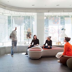 A group of people sitting on a couch in a room with a large window.