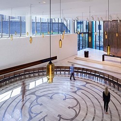 A large room with a large glass wall and a couple people walking.