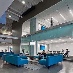 A group of people sitting in a room with blue couches.