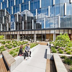 A man and woman sitting on a bench outside of a building.