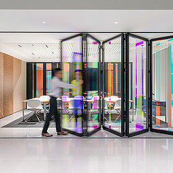 A person standing in front of a glass door with colorful lights.